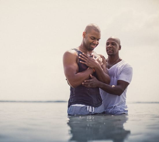 Man baptizing another man outside in a river
