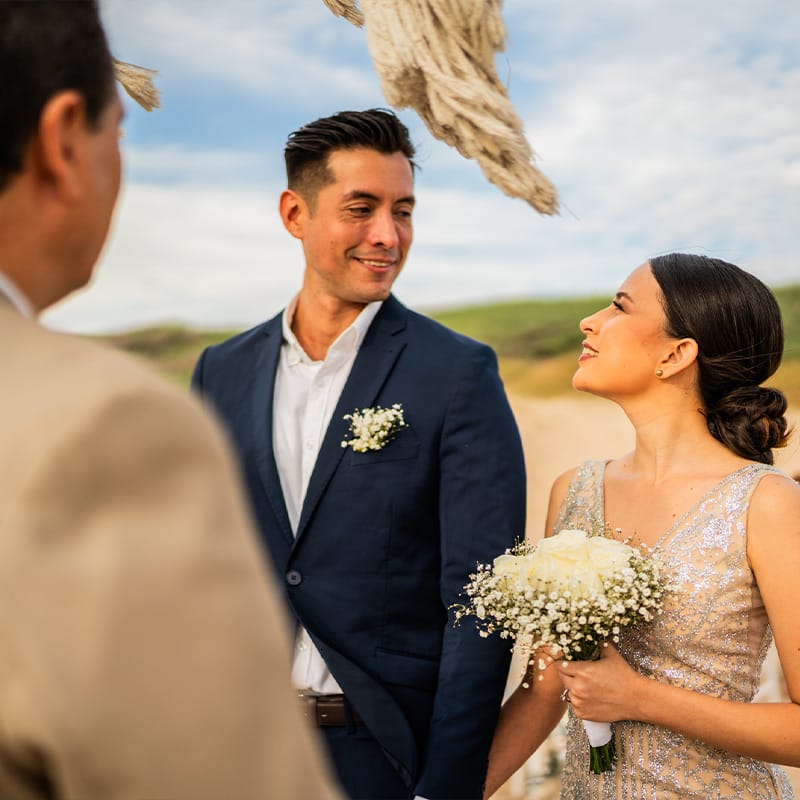 A happy multicultural couple being wed on the beach.