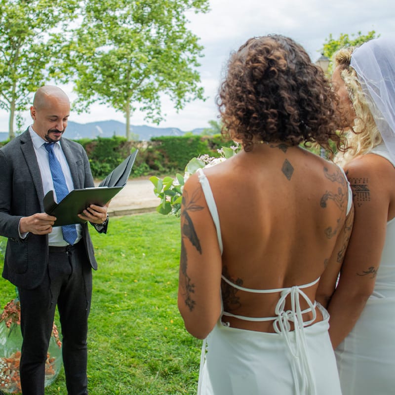 A minister performing a spiritual outdoor wedding ceremony for a bilingual couple.
