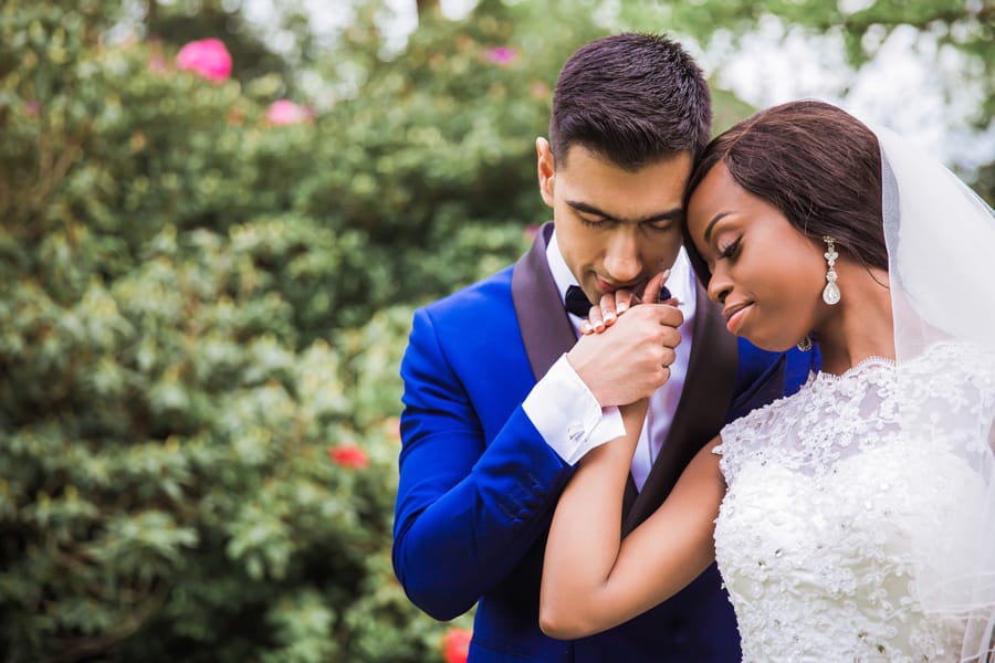 Newlywed groom kissing new bride's hand during spring wedding