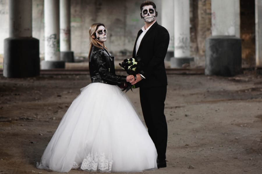 Bride and groom with skull makeup holding hands at samhain wedding