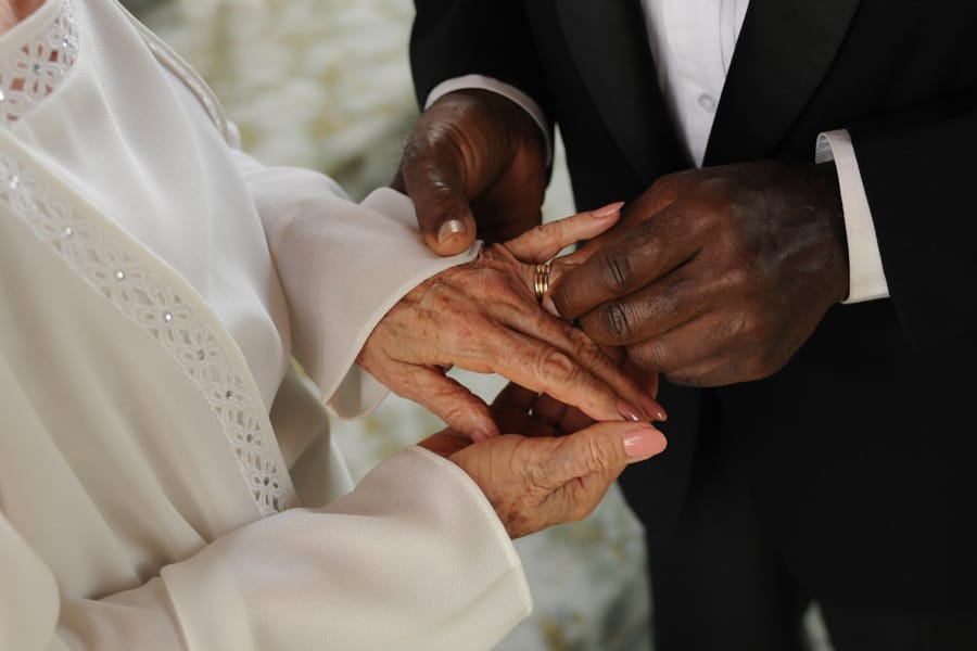Elderly groom putting wedding ring on senior bride's finger