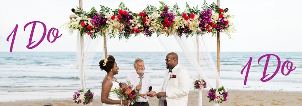 A happy couple being wed at a beach.